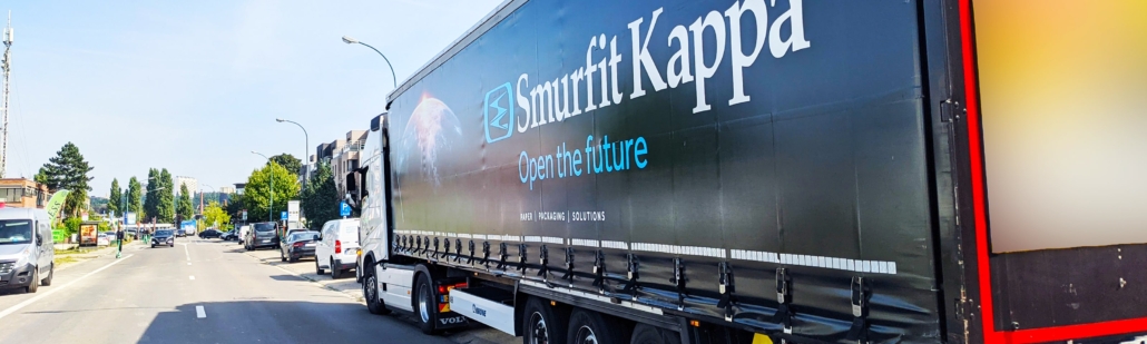 Een smurfit kappa vrachtwagen die op de weg rijdt.