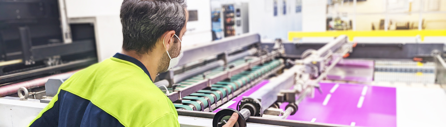 An employee of Smurfit Kappa Drogenbos works with a hi-tech printer that prints a display with graphic design.