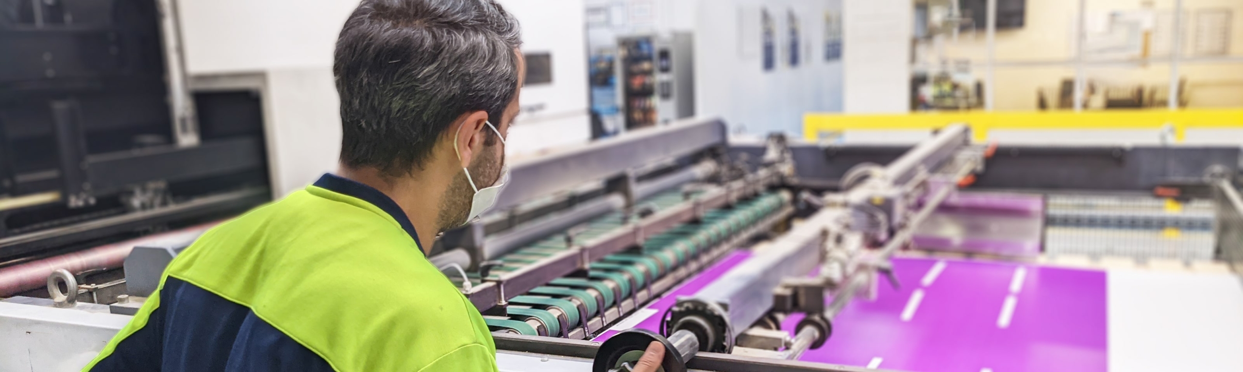 An employee of Smurfit Kappa Drogenbos works with a hi-tech printer that prints a display with graphic design.