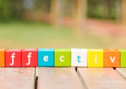 A beautiful colourful picture with wooden cubes in different colours that have a letter on each side. The cubes next to each other spell the word 'effective'